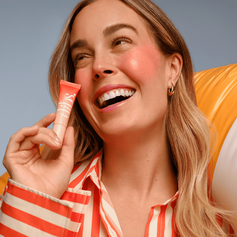 Woman holding a liquid blush tube and a pool float with a gray background