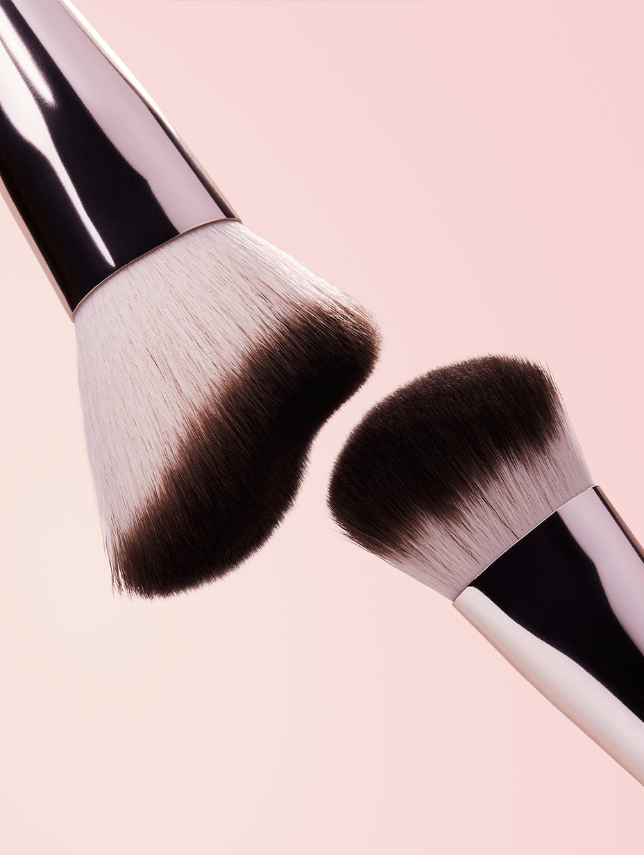 Two sides of makeup brush with black bristles on a pink background