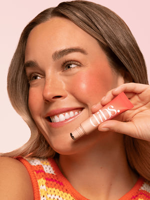 Woman holding Cool Blush Cheek Stain with visible brand name "dibs" against a pink background
