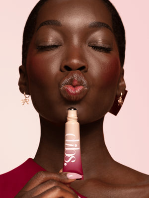 Woman holding a Cool Blush Cheek Stain tube with 'dibs' branding against a pink background