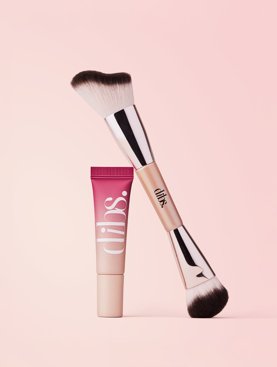 Makeup brush and tube of liquid blush on a pink background